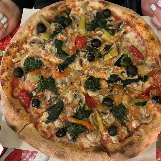 Pizza na cienkim cieście ze szpinakiem, pieczarkami, papryką i oliwkami, widok z góry